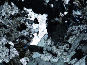 Same as above, crossed polarisers. Note the grey to black, and locally anomalous blue birefringence colours of zoisite.